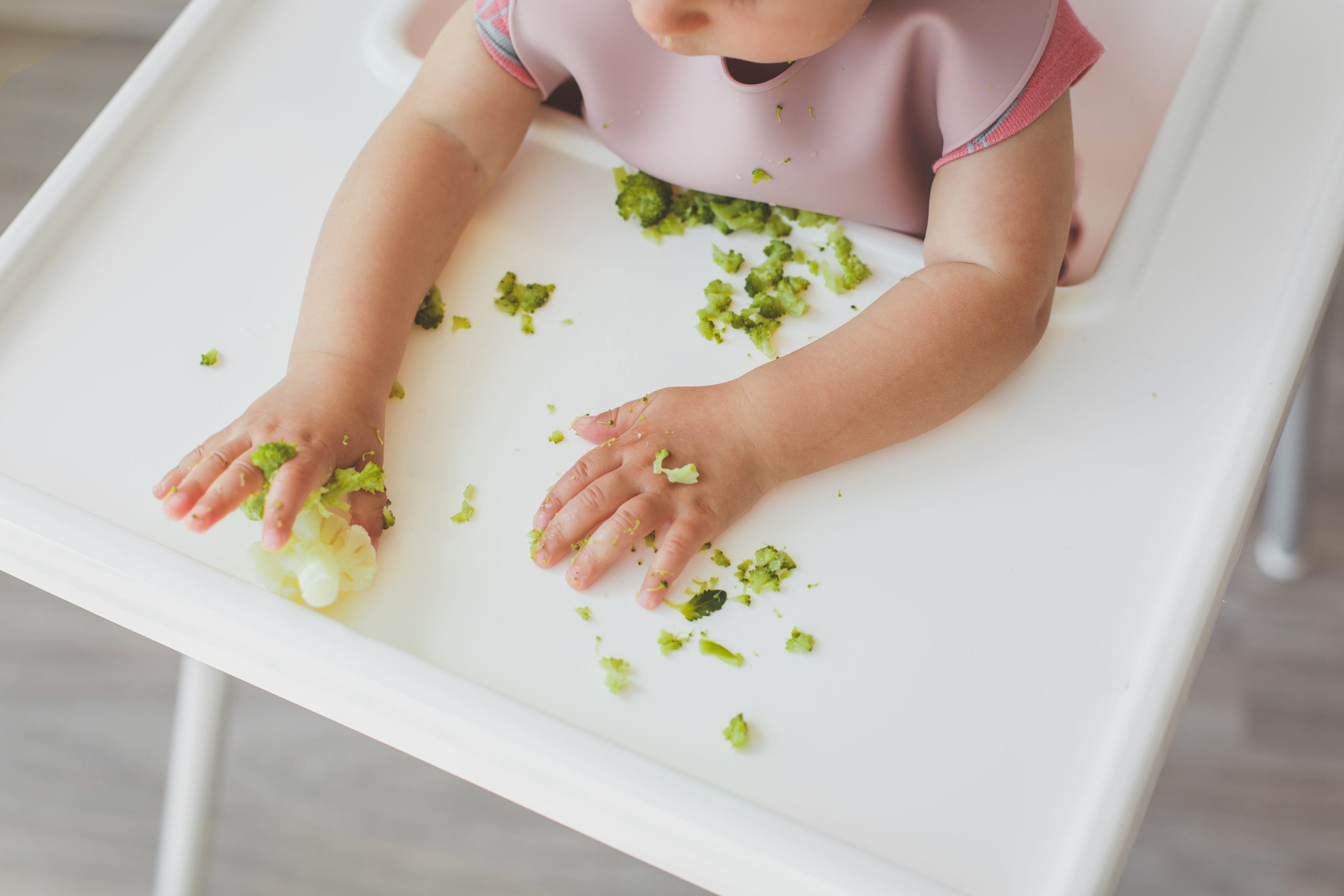 Children’s,Hands,On,A,Table,With,Pieces,Of,Broccoli,And